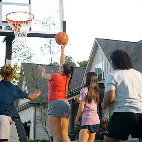 Group of athletes playing basketball in a driveway with the Excel TF-500 basketball.